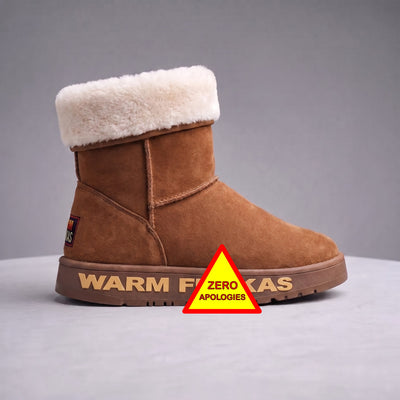 A brown suede ankle boot with a thick white wool fur collar, shown in profile on a grey background. The brand name is embossed along the sole, with a red and yellow 'ZERO APOLOGIES' sticker overlaid on the front.