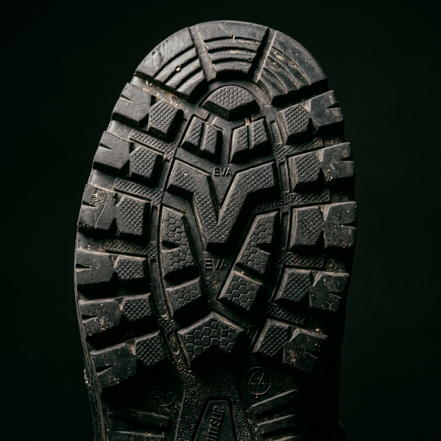 Close-up of a black shoe sole with tread pattern on a black background