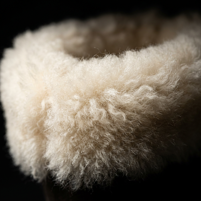 Close-up of a fluffy Merino wool white cuff on a black background